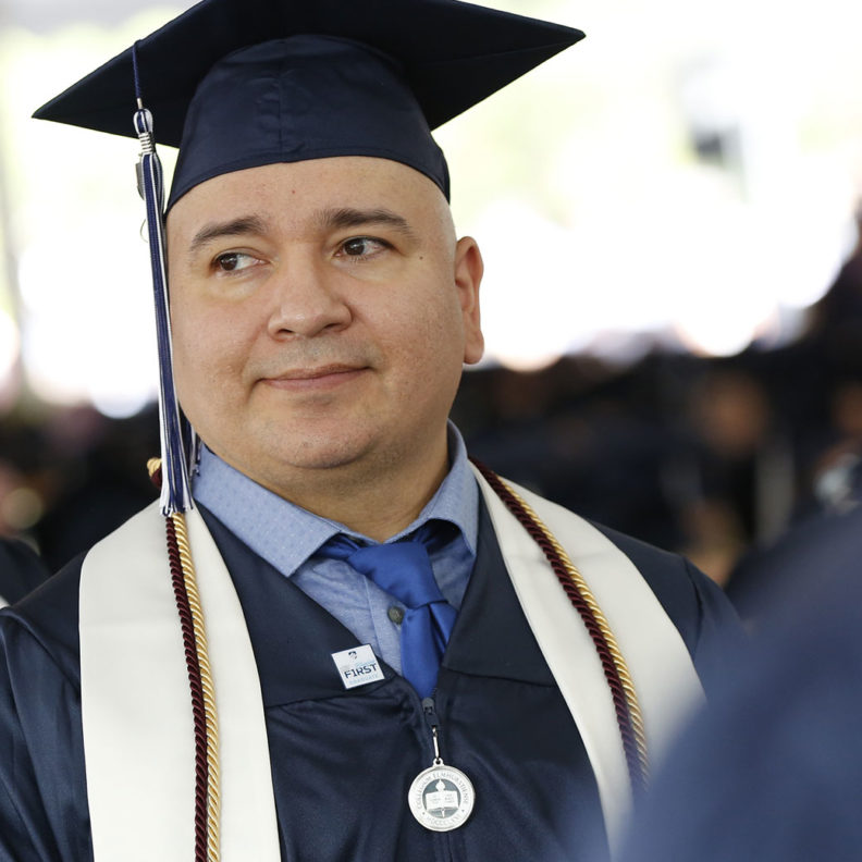 A student stands during Elmhurst University's 2019 undergraduate Commencement ceremony.