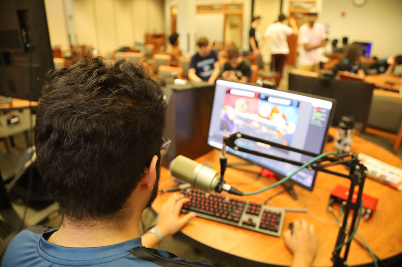 Student sitting at a computer talking into a microphone.