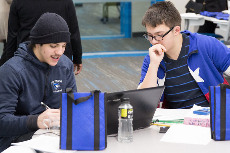 Two Elmhurst College in academic centers students focus on a laptop while studying in the Learning Center within the A.C. Buehler Library.