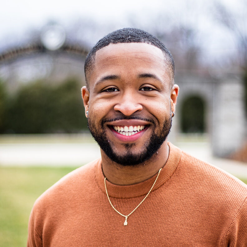 Man smiling in front of Elmhurst University 幸运艇 gates