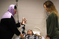 An occupational therapy instructor demonstrates on a patient in a classroom setting at Elmhurst University.